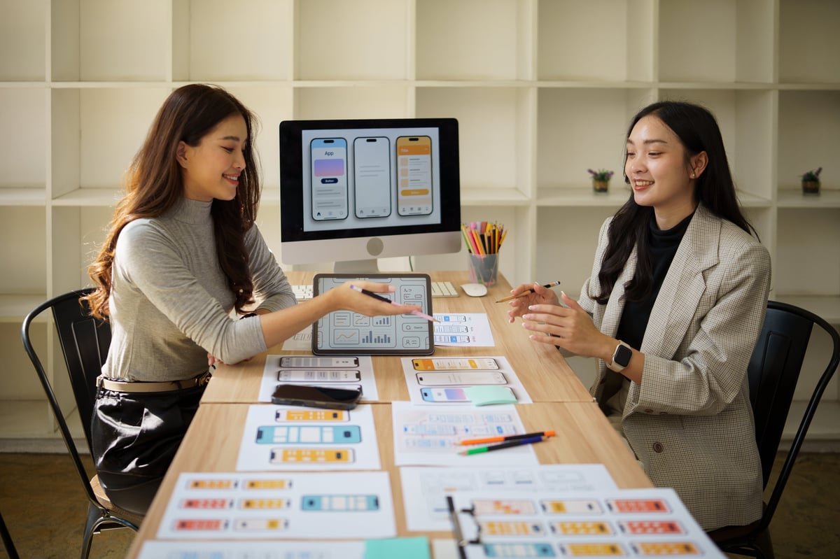 Designers reviewing website wireframes and printed layouts at a desk