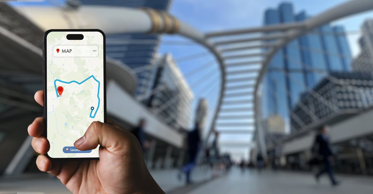 Hand holding a smartphone showing a GPS map route in an urban street
